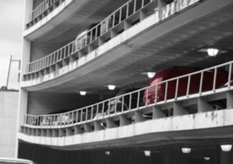 Multi-level parking garage with curved concrete slabs showing visible water staining and surface deterioration on a post tension slab.